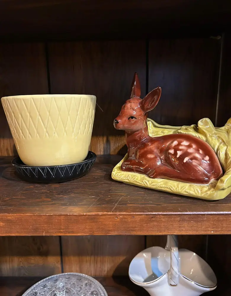 Vintage yellow planter and a ceramic fawn figurine on a wooden shelf at Chaintiques